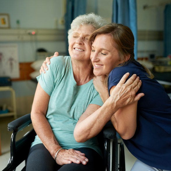 vrouw knuffelt moeder in rolstoel